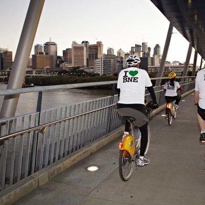 Two men on bicycles riding over a bridge on the Brisbane River